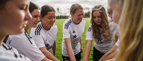 Fodboldpiger står i rundkreds på fodboldbanen på Sædding Efterskole