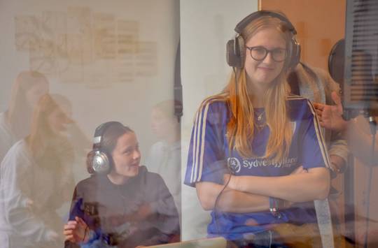 En pige står med hørebøffer på i lydstudiet på Sædding Efterskole