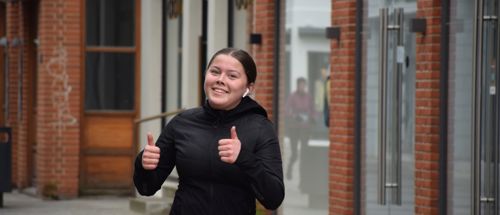 Efterskolepige viser tumps up mens hun løber halvmarathon i Holstebro med Sædding Efterskole