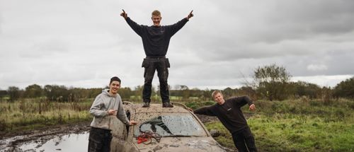Efterskoleelever står ved markræs bil på en mudret mark