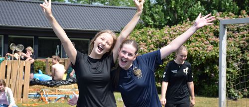 To piger efterskolepiger spreder begejstret armene i vejret i Sædding Efterskoles have