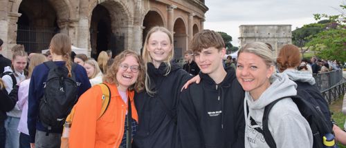 To elever og to lærere fra Sædding Efterskole står i Rom foran en seværdighed og smiler til kameraet