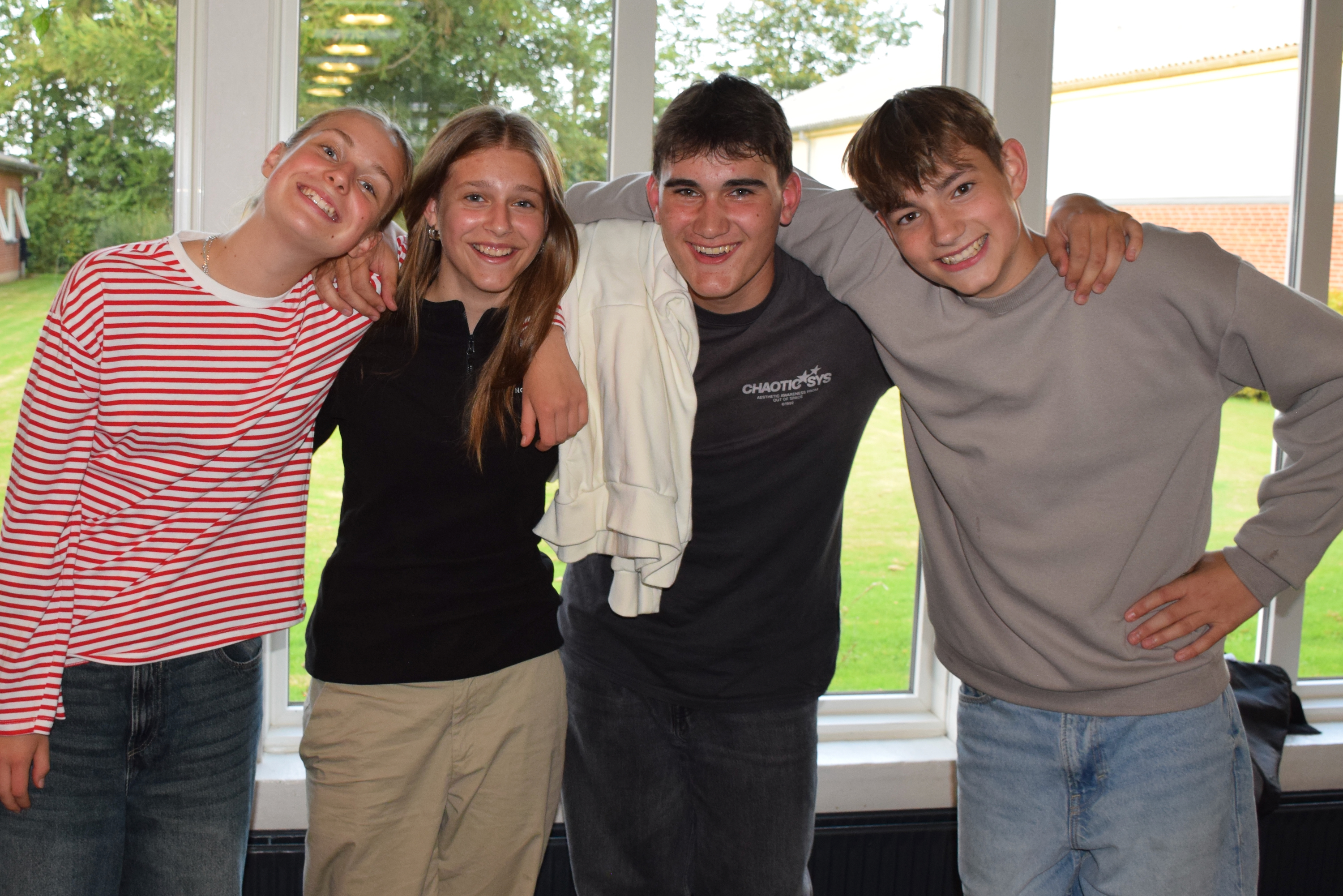 En flok glade efterskoleelever fra Sædding Efterskole, står med armene rundt om hinanden og smiler til kameraet.